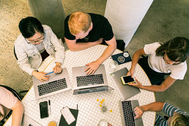 Group working on laptops at table, focusing on auto inventory ads