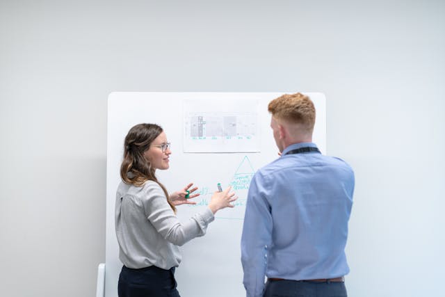 Two individuals standing in front of a whiteboard discussing personalization in account-based marketing