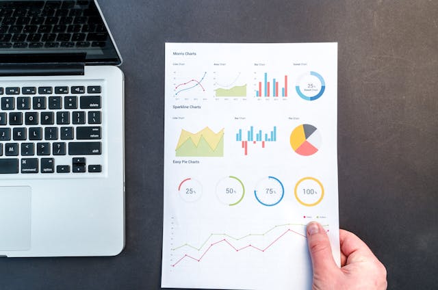 Businessman holding paper with graphs and statistics on desk,